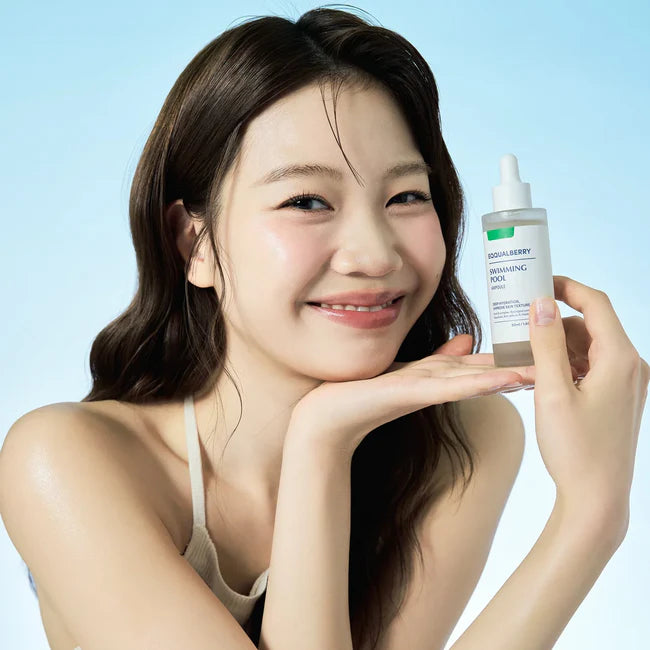 Woman holding a skincare product against a light blue background