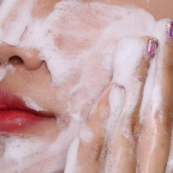 Close-up of a person applying foamy soap to their face.