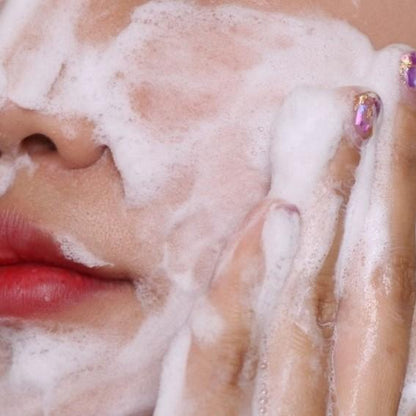 Close-up of a person applying foamy soap to their face.