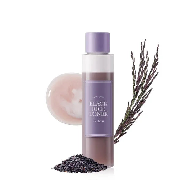 Black rice toner bottle with a white cap, surrounded by black rice powder and lavender on a white background.