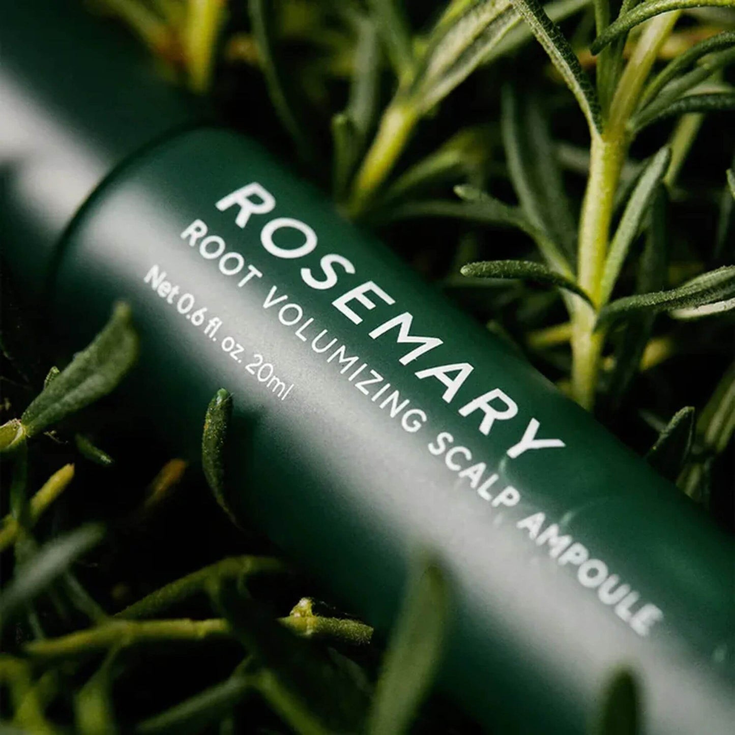 Rosemary root volumizing scalp ampoule bottle with green leaves in the background
