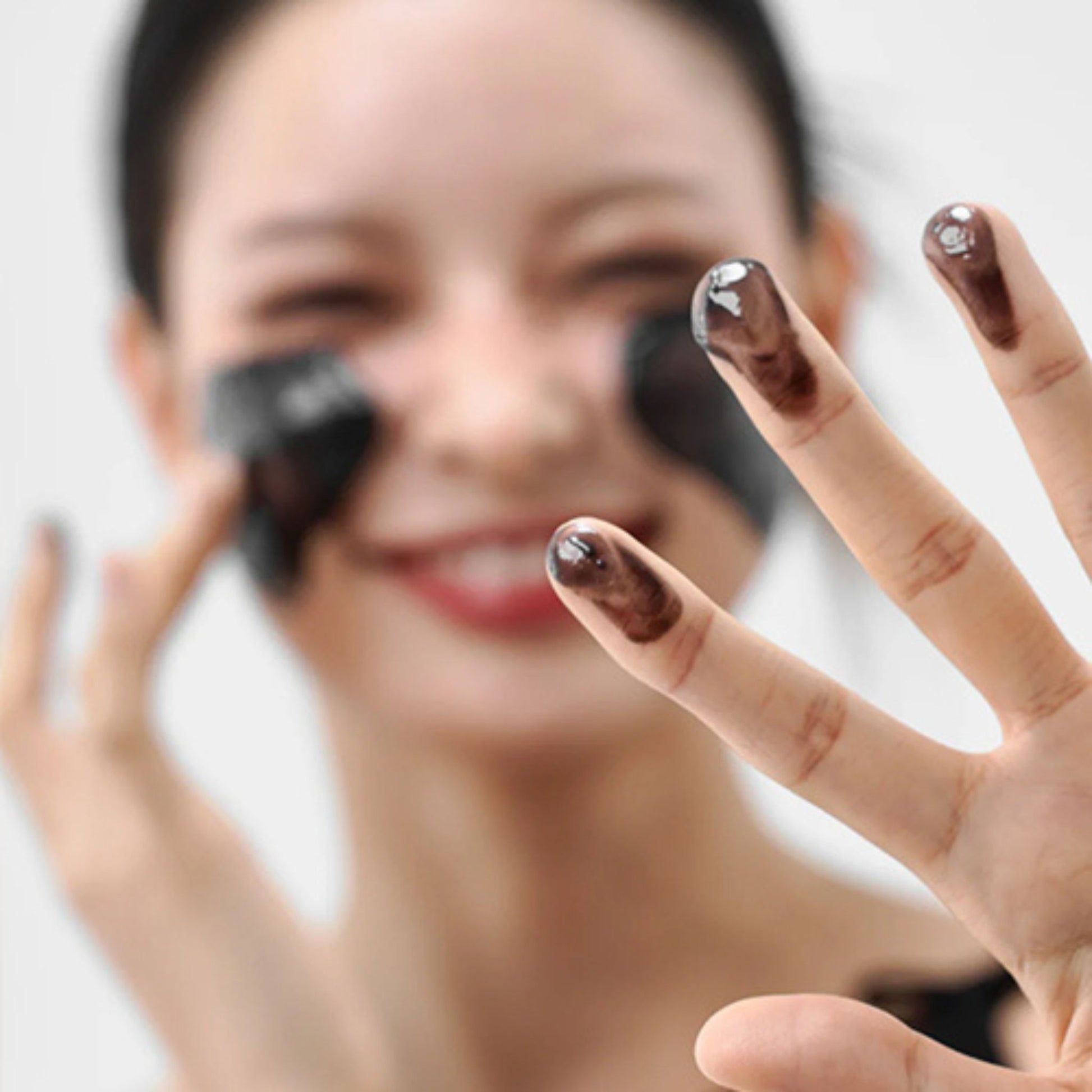 Woman with dark nail polish showing her hand against a neutral background