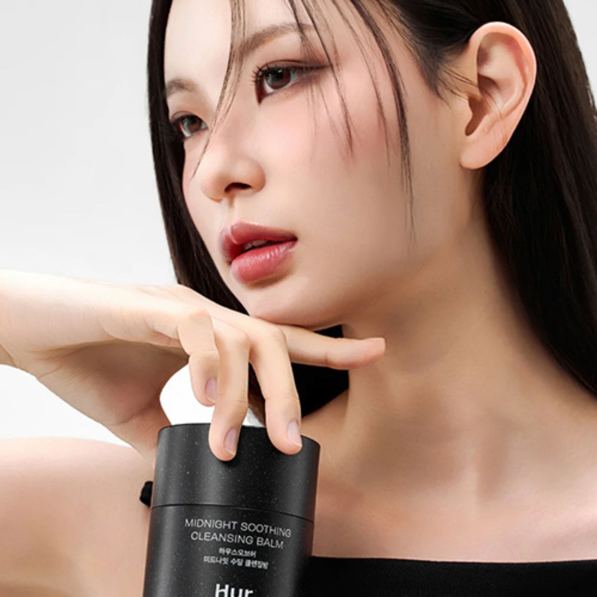 Woman holding a black skincare product with visible branding
