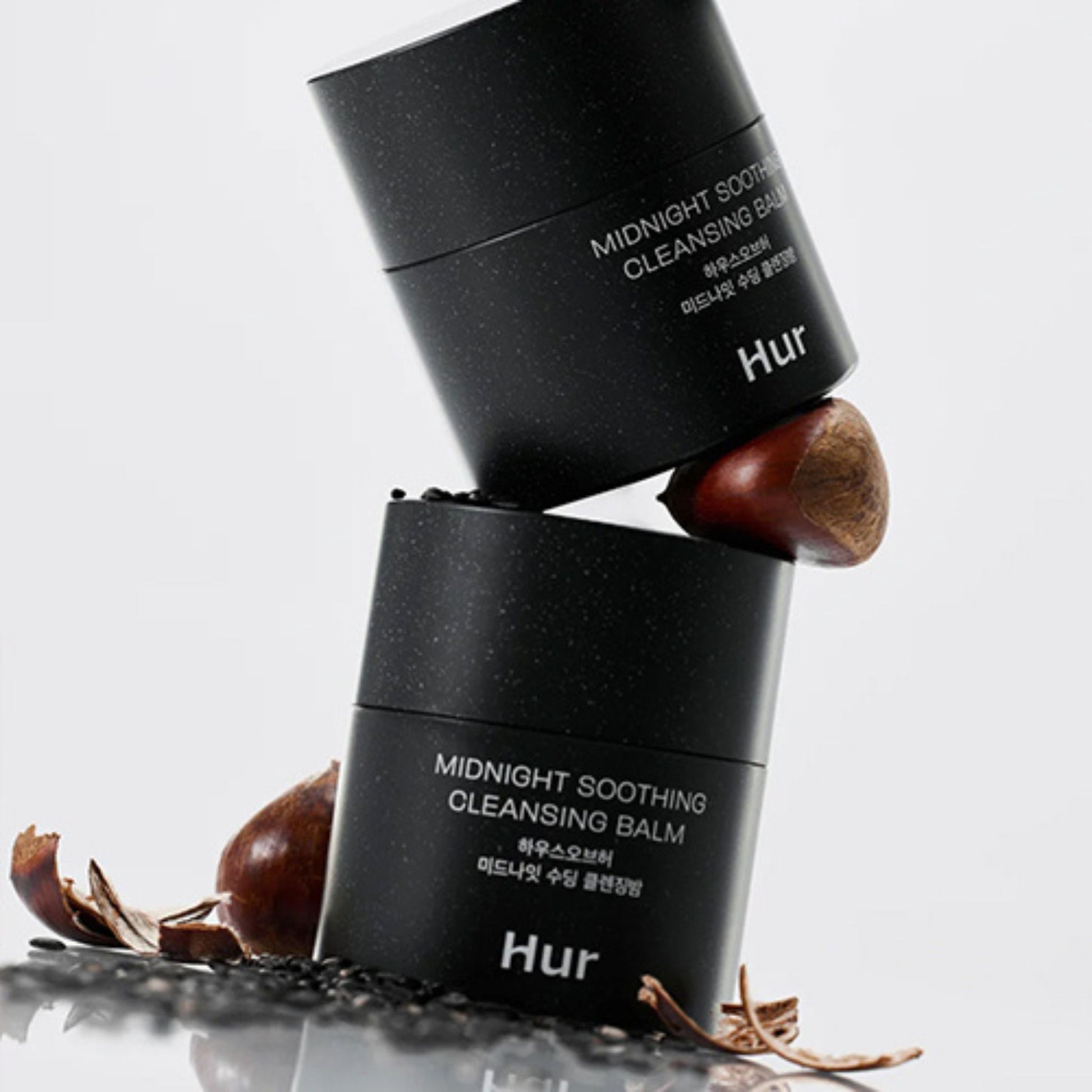 Two black containers of Hur Midnight Soothing Cleansing Balm with chestnuts on a light gray background
