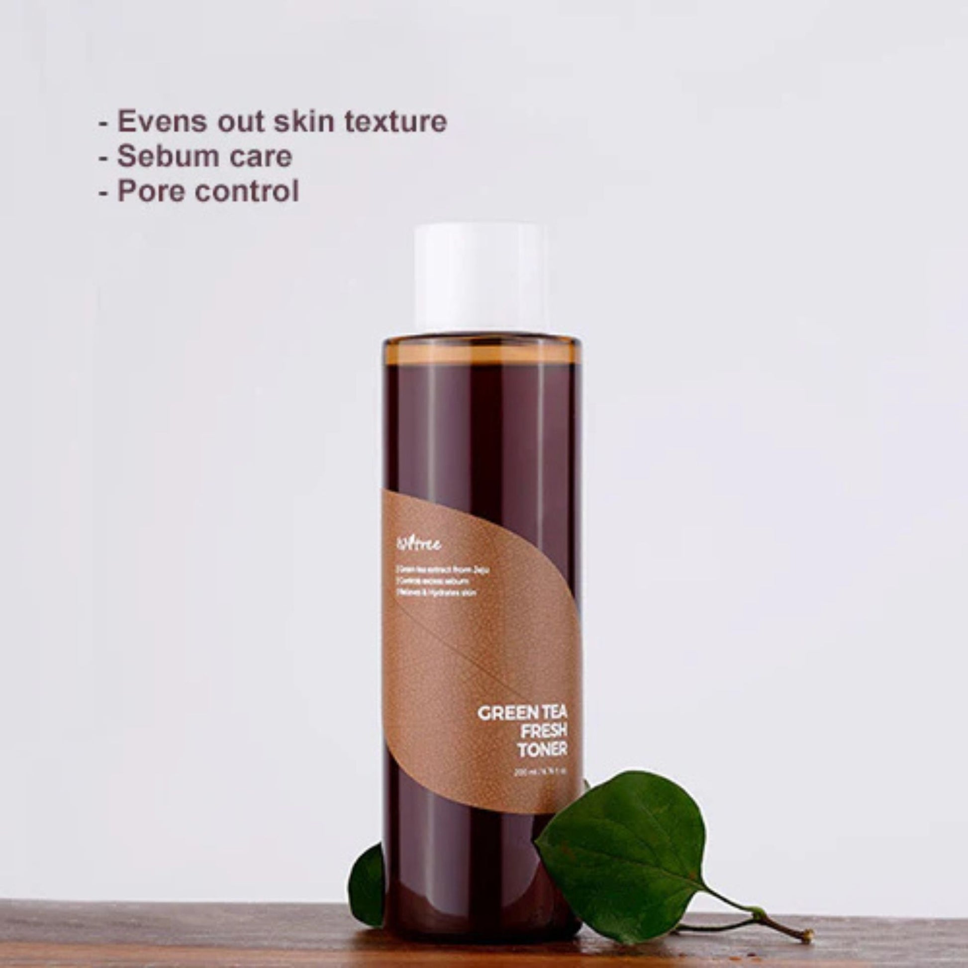 Bottle of Green Tea Fresh Toner with green leaves on a light gray background