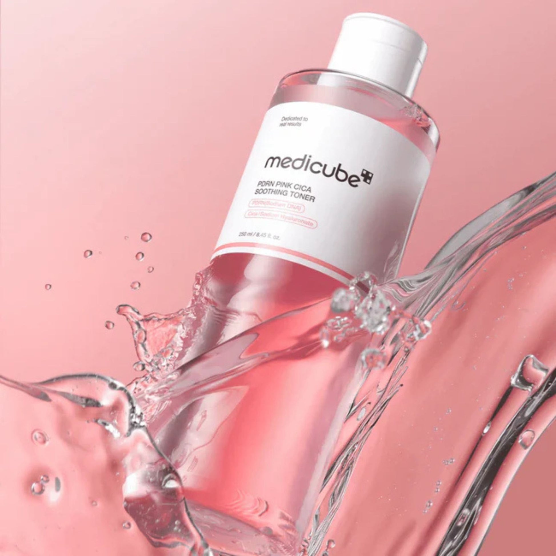 Medicube toner bottle with water splashes on a pink background