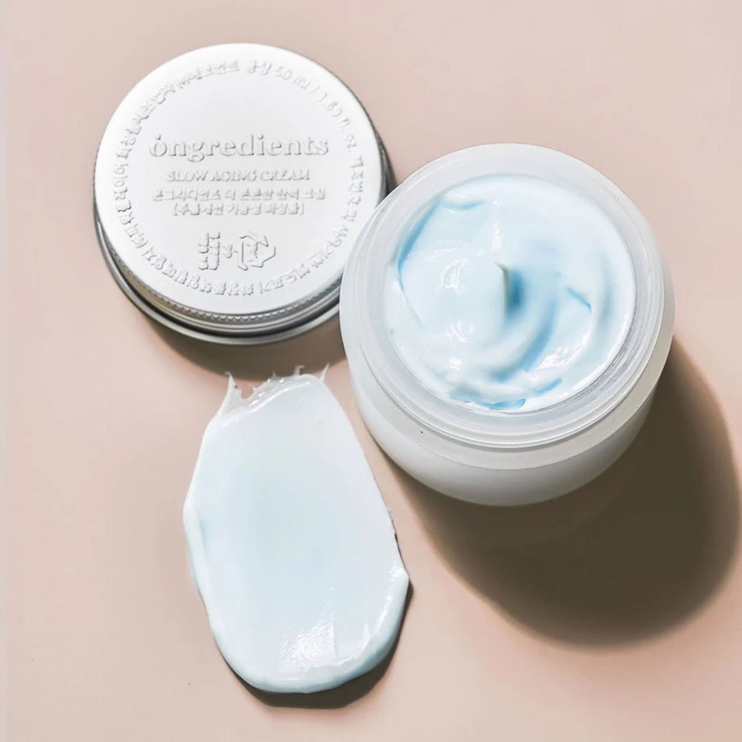 Skincare cream jar with lid and swatch on a beige background