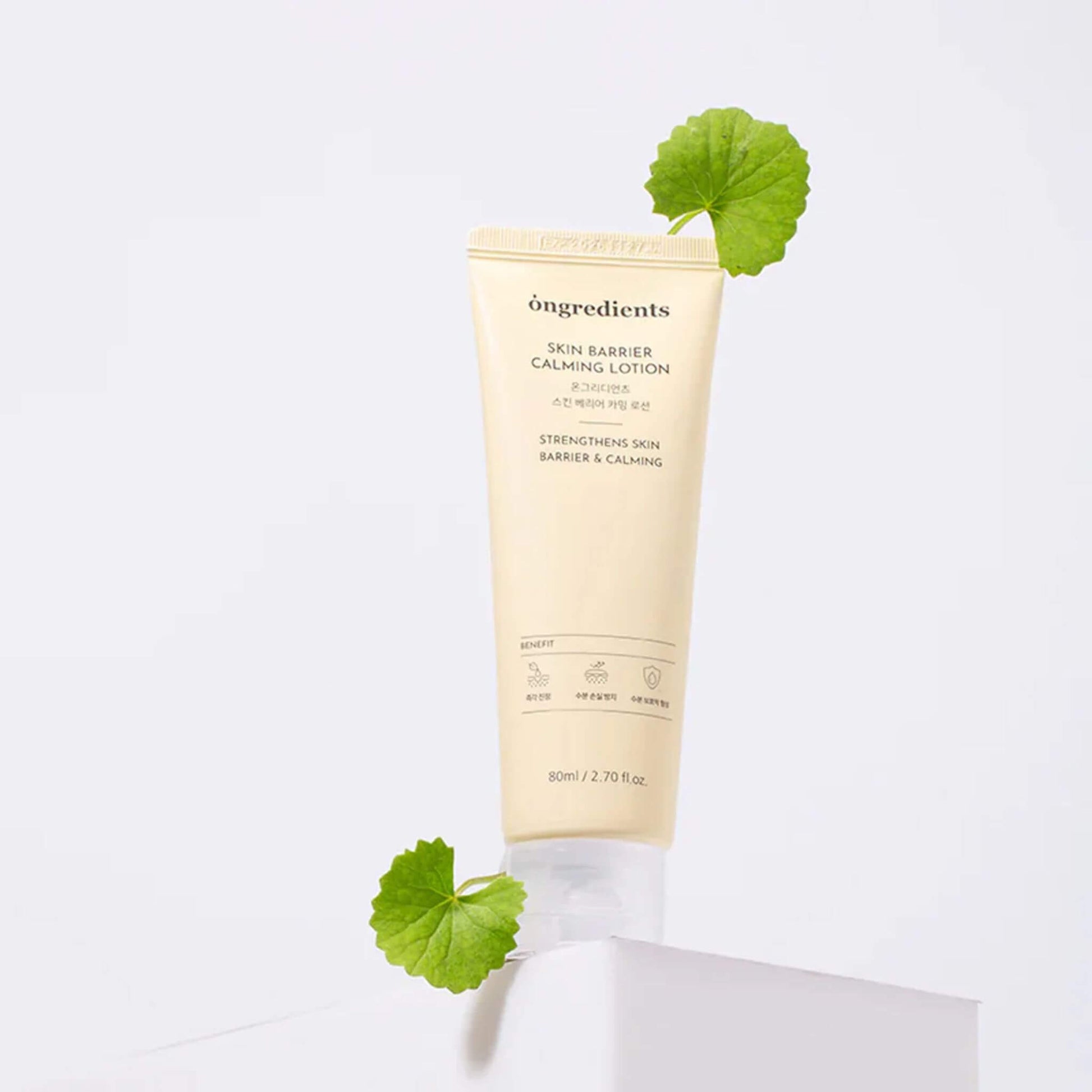 Tube of ongredients skin barrier calming lotion with green leaves on a white background