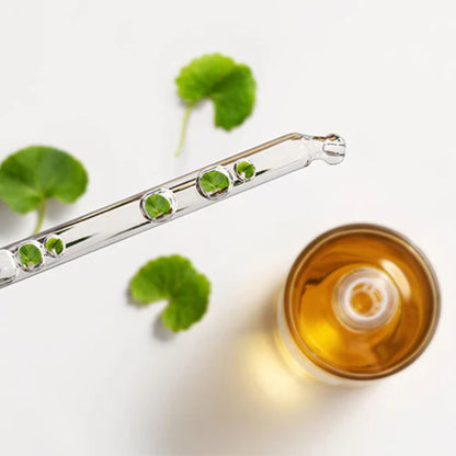 Glass dropper with green liquid and a small container of yellow liquid on a white background