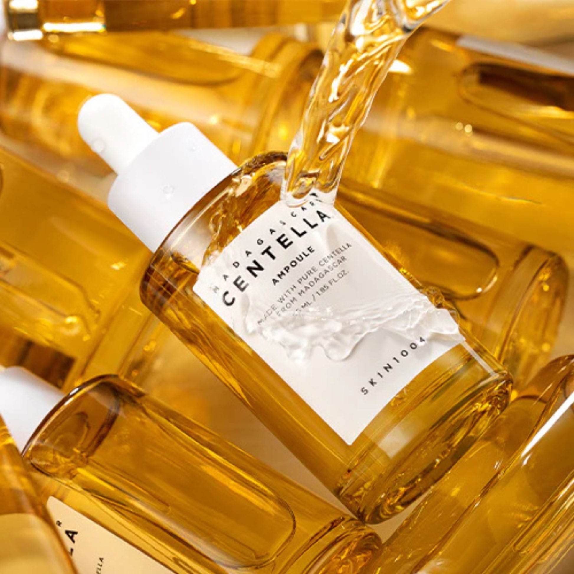 Bottle of Centella Ampoule with dropper being poured into another bottle, surrounded by similar bottles.